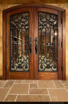 an ornate wooden door with glass panels and wrought iron work on the top paneling