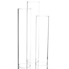 two tall clear vases sitting next to each other on a white surface, one is empty