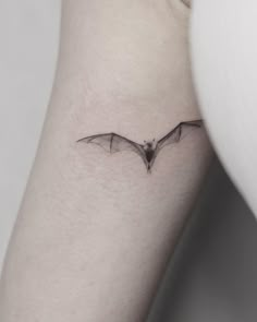 a small bat tattoo on the arm