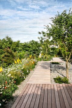 a wooden walkway surrounded by flowers and trees