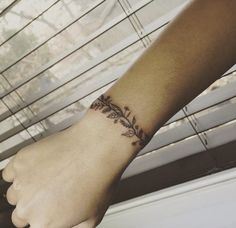 a woman's arm with a tattoo on it and a window blind in the background