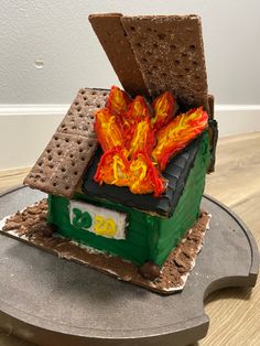 a cake made to look like a house with fire coming out of the roof and crackers on top