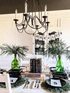 a dining room table is set with green vases and books