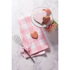 two heart shaped cookies on pink napkins next to a whisk and utensil