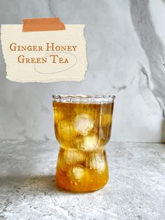 ginger honey green tea in a glass cup on a marble surface with a sign that reads ginger honey green tea