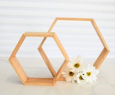 two wooden hexagonals with flowers in front of them on a white surface