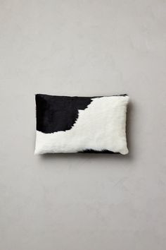 a black and white cowhide pillow on a gray wall