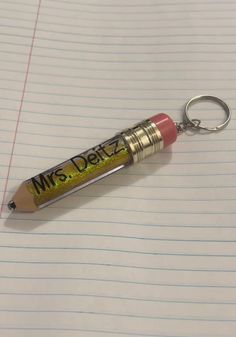 a pencil keychain with the word miss deliz on it sitting on top of lined paper