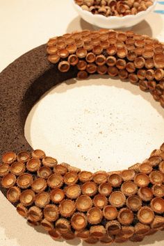 two bowls filled with nuts sitting on top of a counter next to a wreath made out of wood