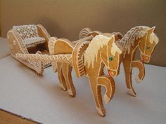 two wooden horses pulling a carriage made out of paper