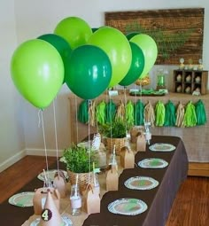 a table topped with lots of green balloons and desserts on top of tables covered in brown paper