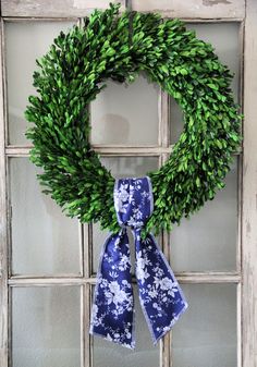 a wreath with blue and white flowers hanging on a window sill in front of a door