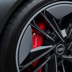 the front wheel of an audi car with red brake pads and black spokes on it