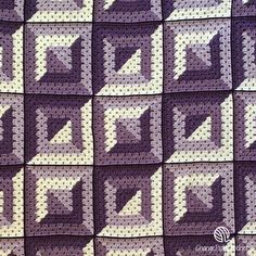 a purple and white crocheted blanket with squares on it, in the shape of an arrow