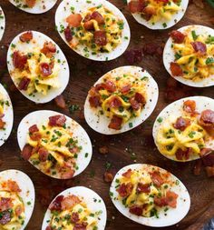 deviled eggs topped with bacon and cheese on a wooden platter