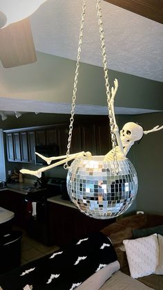 a mirror ball hanging from the ceiling with a skeleton on it's back and arms