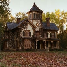 an old house with ivy growing on it's roof and windows, in the fall