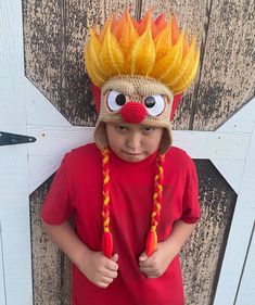 a young boy wearing a knitted fireman hat with braids on his head