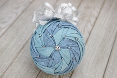 an ornament made out of fabric on a wooden floor with white ribbons and bows