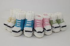 six pairs of knitted baby booties in different colors and sizes, lined up against each other