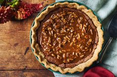 a pie sitting on top of a wooden table next to a knife and fork in front of it