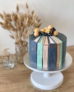 a cake decorated with books on top of a wooden table next to some dried flowers