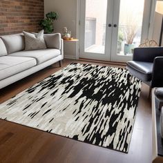 a living room filled with furniture and a white rug on top of a hard wood floor