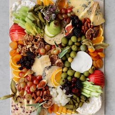 an assortment of fruits and cheeses on a platter with grapes, oranges, apples, pears, walnuts