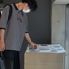 a woman wearing a face mask standing next to a stack of boxes with the lid open