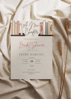 a wedding card with books on it sitting on top of a white bed sheet next to two dead grass