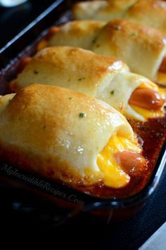 hotdogs wrapped in bread and cheese on a baking sheet