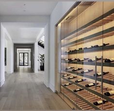 a long hallway with wooden shelves and shoes on the wall in front of it, leading to an entry way