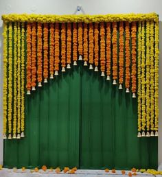 an entrance decorated with yellow and orange garlands on the door to a green building