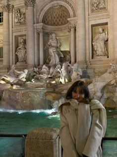 a woman standing in front of a fountain at night