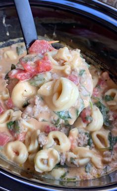 a spoon full of pasta and meat in a crock pot