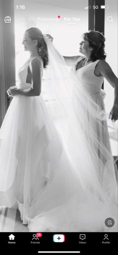 two women in white dresses standing next to each other and one is wearing a veil