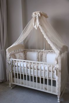 a white crib in a room with curtains and pillows