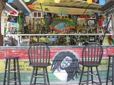 three wooden chairs sitting in front of a surfboard bar with pictures on the wall