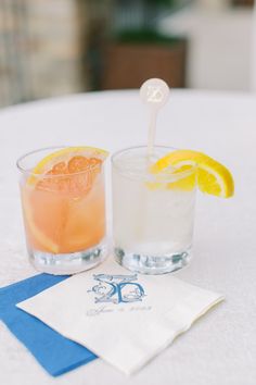 two glasses filled with drinks sitting next to each other on top of a white table