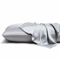 two pillows with satin sheets on them sitting next to each other in front of a white background