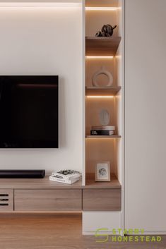 a flat screen tv sitting on top of a wooden shelf in front of a white wall