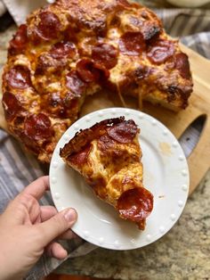 a slice of pepperoni pizza on a white plate next to a wooden cutting board