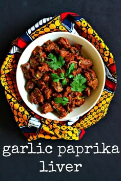 a white bowl filled with meat and garnished with parsley next to a colorful napkin