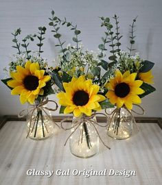 three glass vases with sunflowers and baby's breath