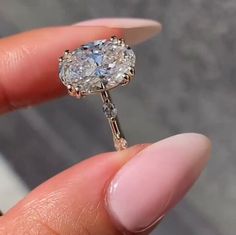 a close up of a person's hand holding a ring with a diamond in it