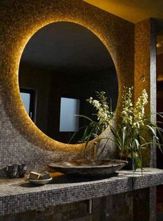 a bathroom with a large round mirror above the sink and flowers in front of it