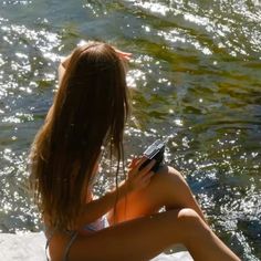 a woman sitting in the water looking at her cell phone