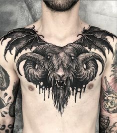 a man with tattoos on his chest is wearing a demon head and wings tattoo design