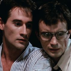 two men with glasses are looking at something in front of their face and one has his arm around the other man's shoulder