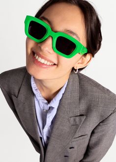 a woman in a suit and green sunglasses